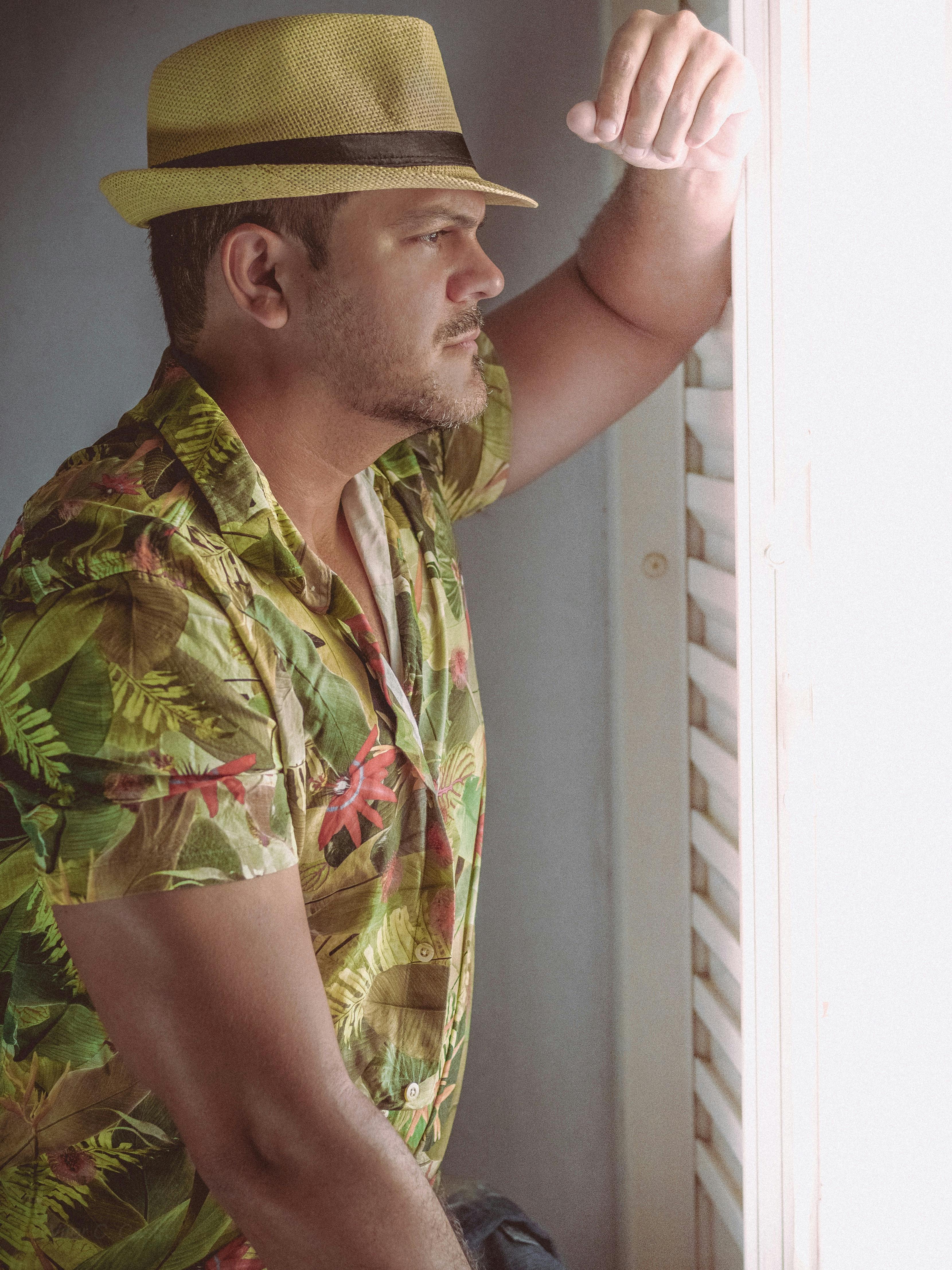 一名穿着花卉衬衫、戴着草帽的男子，正凝视着午后的阳光