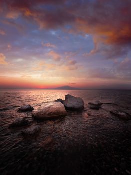 Stunning seascape at dawn with dramatic clouds and calm waters creating a serene atmosphere.