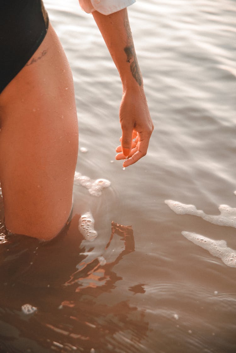 Leg And Arm Of Woman Standing In Water