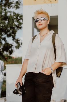 Stylish woman photographer holding a vintage camera outdoors, exuding confidence and trendy vibes.