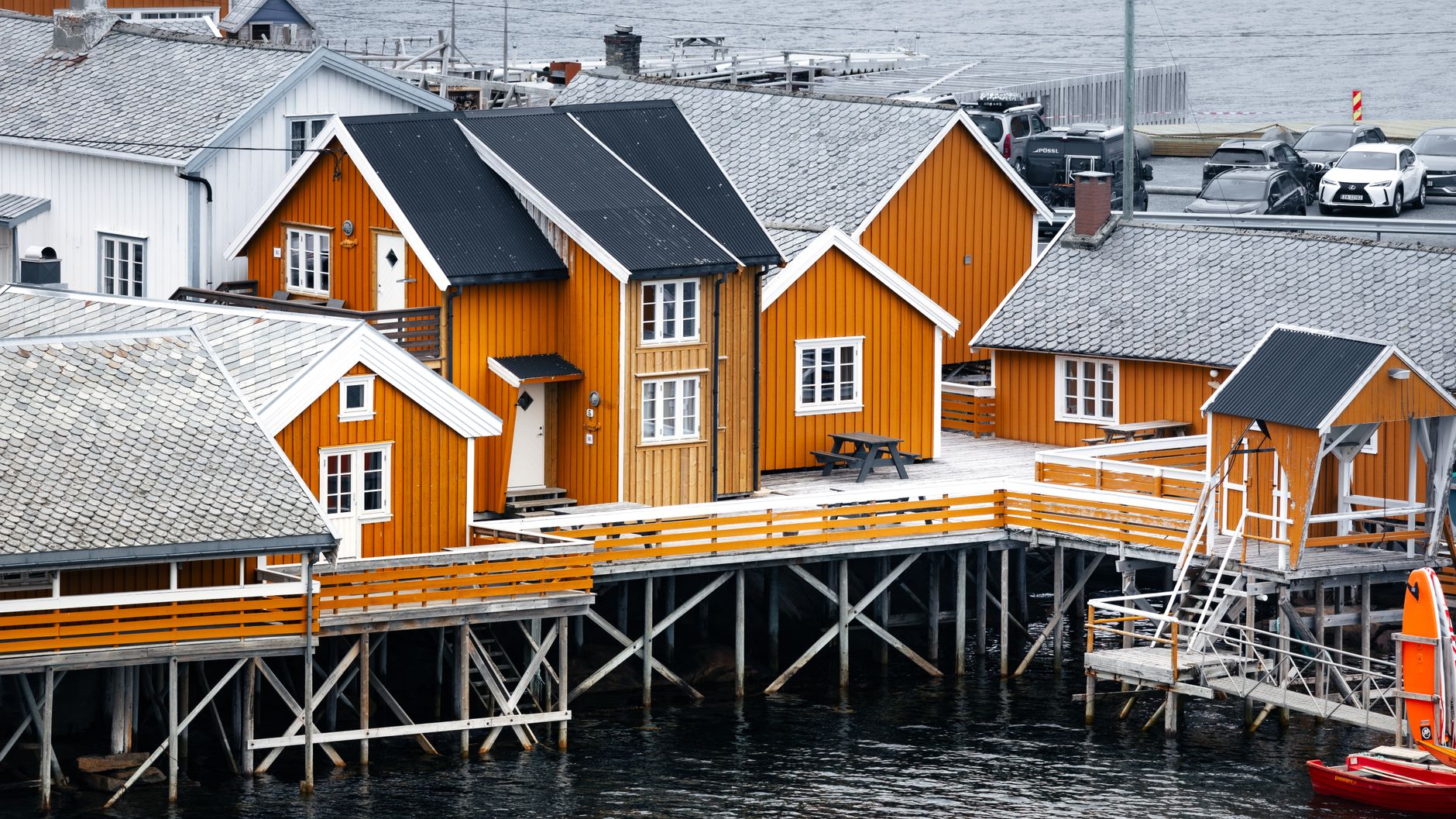 Vibrant orange wooden houses on stilts by the sea in a Norwegian village.