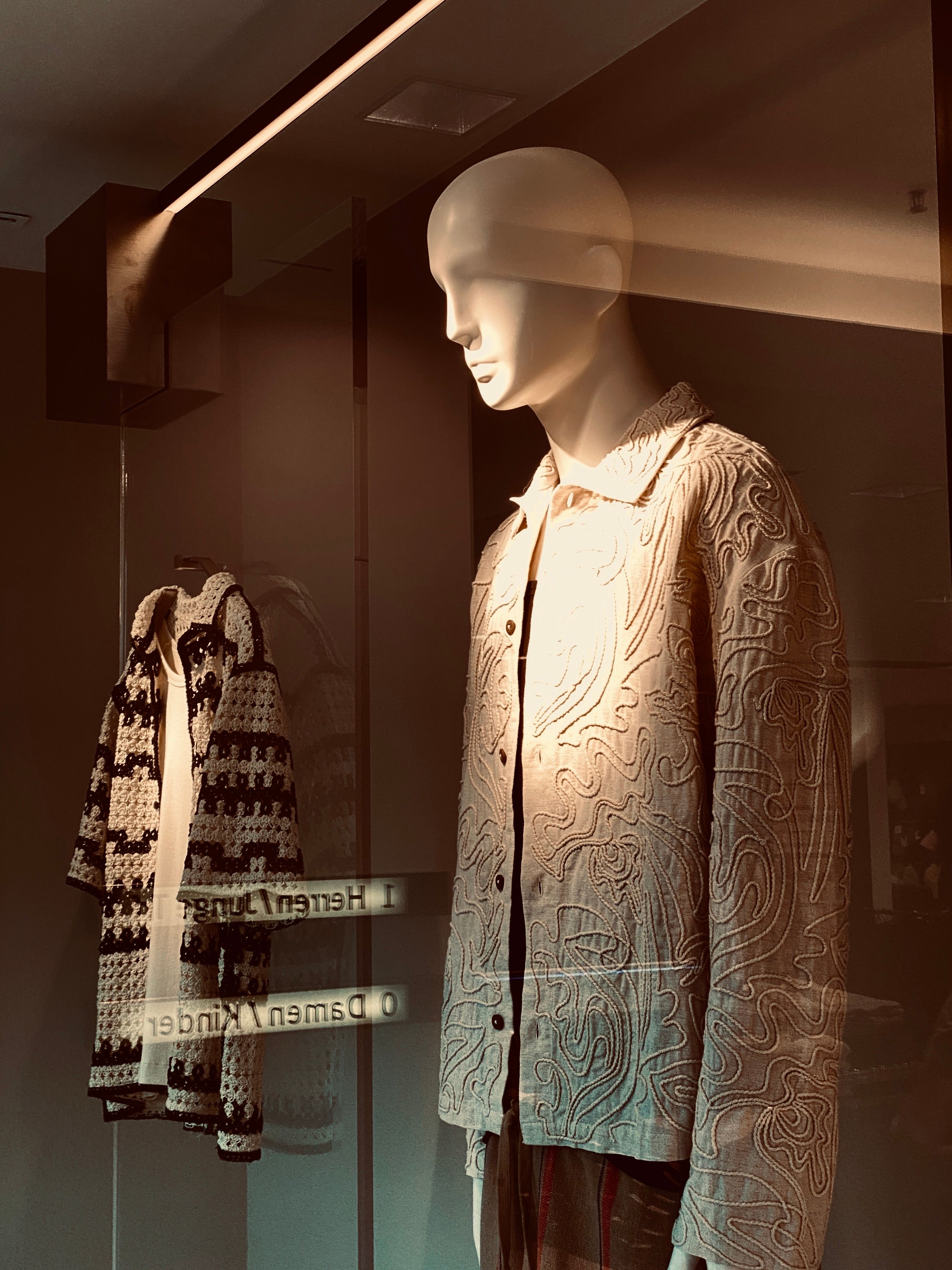 Stylish retail window display featuring mannequins in patterned jackets.