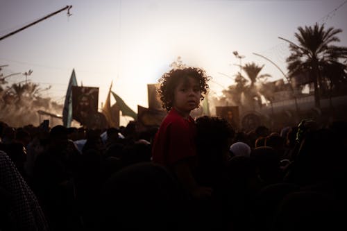 A Child Sitting on a Persons Shoulders in the Crowd at a Parade 