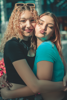 Two smiling women hugging in sunshine, showcasing friendship and joy.