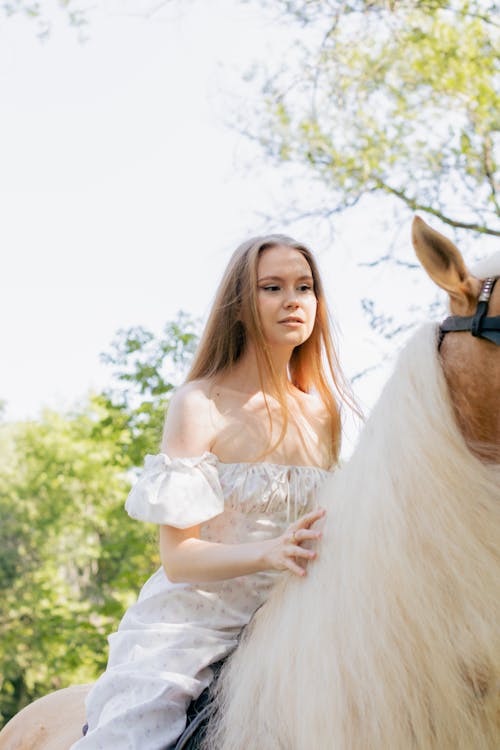 Beautiful Woman in a White Dress Riding a Horse 