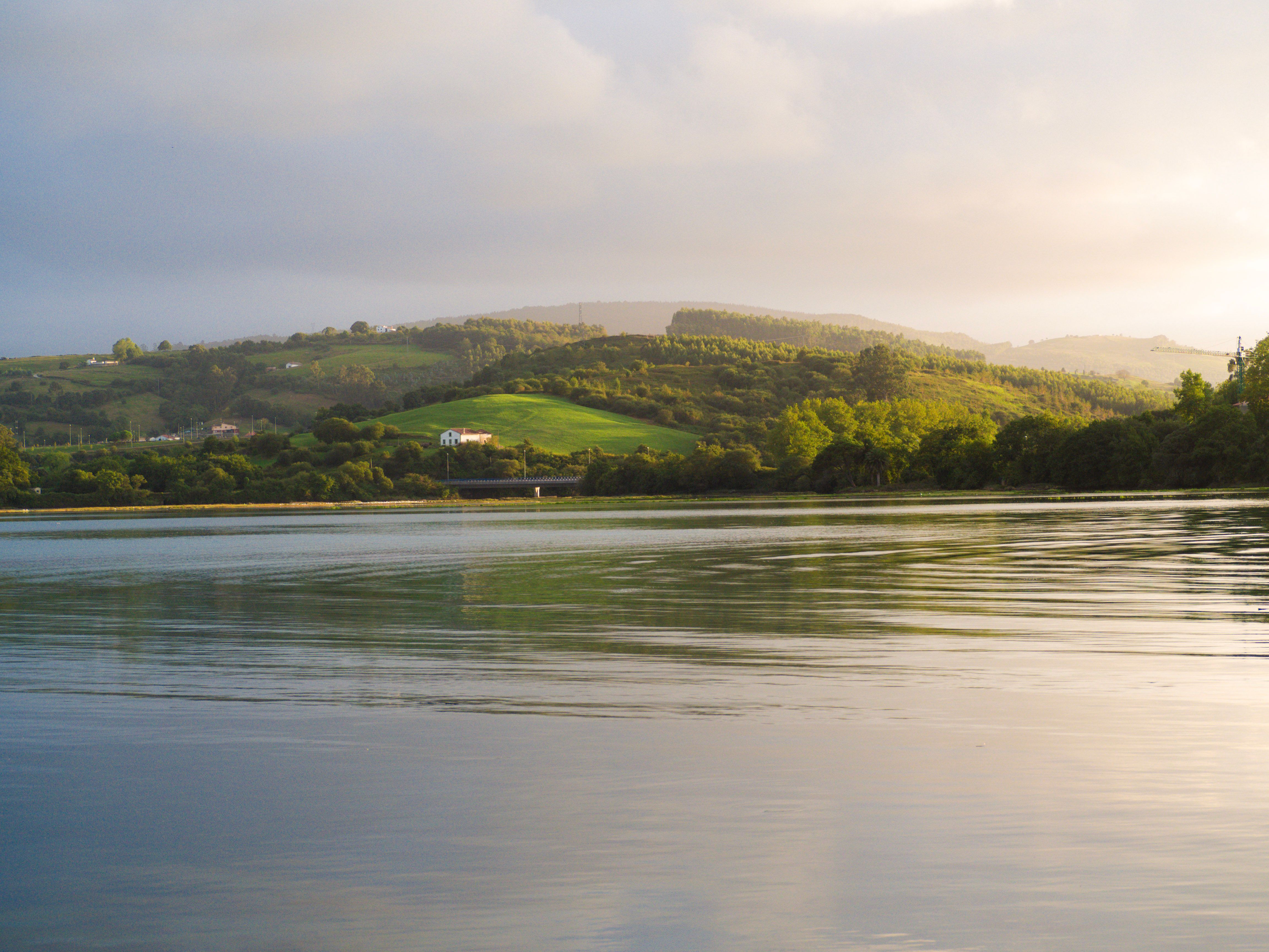 Picturesque landscape of San Vicente de la Barquera with lush hills and calm waters reflecting the serene environment.
