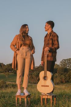 A well-dressed couple poses with a guitar in a sunlit field in Goiás, Brazil.