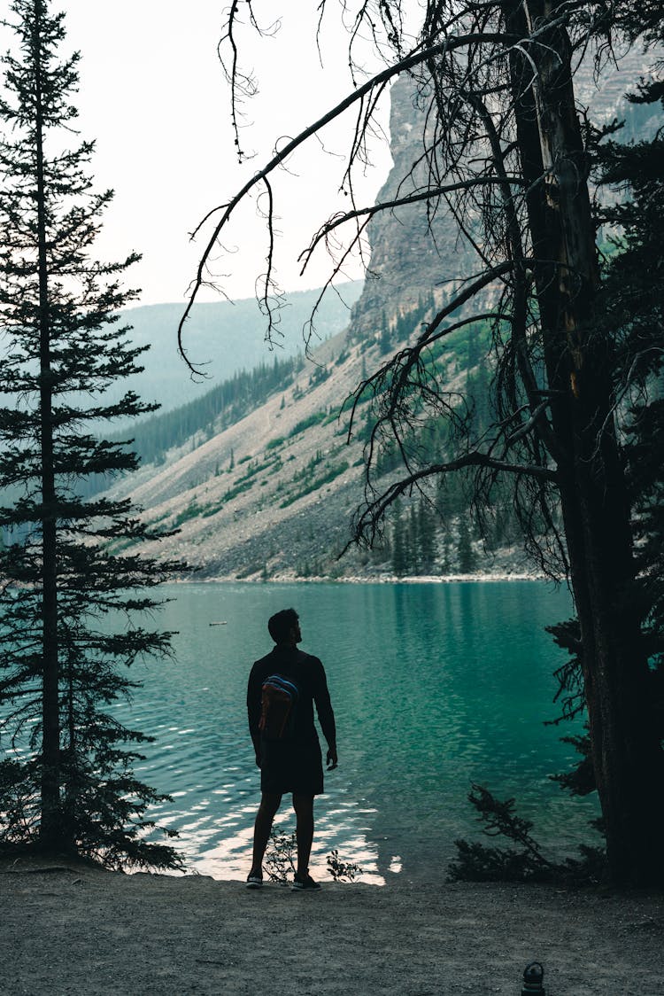 Man With A Backpack Standing On Moraine Lake Shore, Banff, Canada