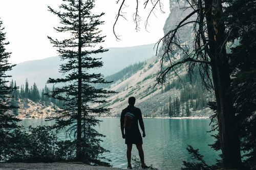 Free Silhouette of a hiker overlooking the turquoise waters of Moraine Lake in Banff, Canada. Stock Photo