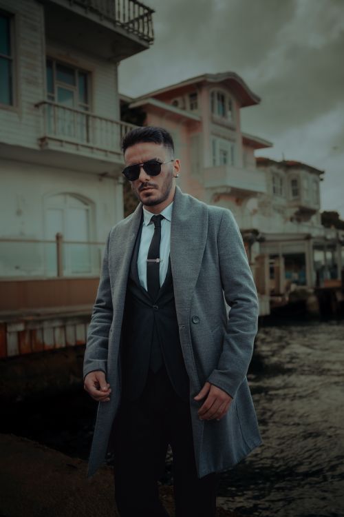 Free Fashionable man in a wool coat and sunglasses near the waterfront in Istanbul, Turkey. Stock Photo