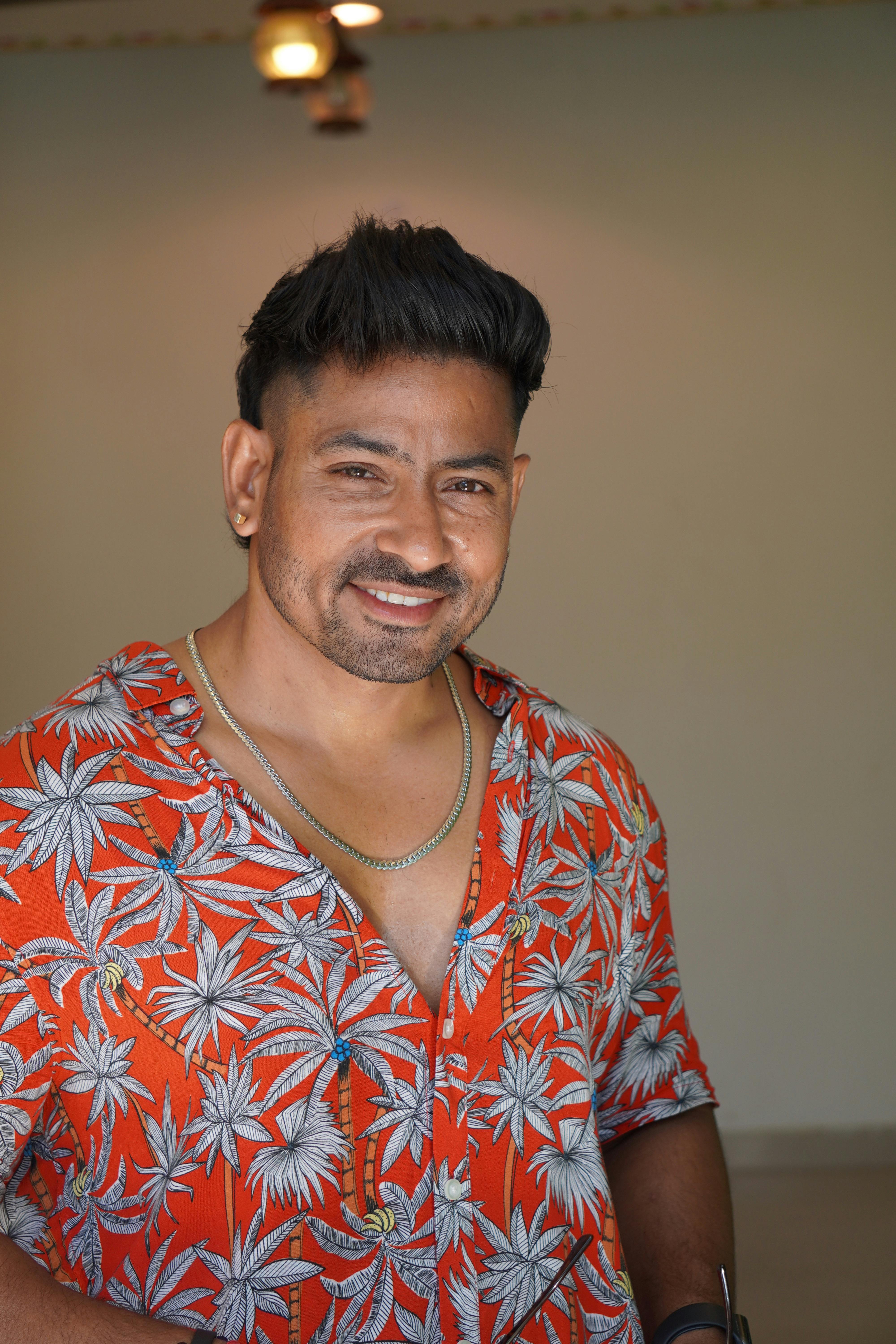 Portrait of a smiling man in a floral print shirt indoors.