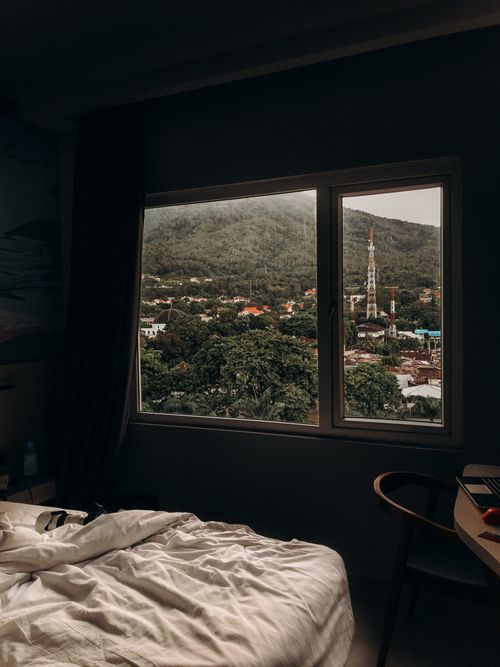 Free A bedroom with a scenic window view of Bitung, North Sulawesi, featuring lush greenery and mountains. Stock Photo