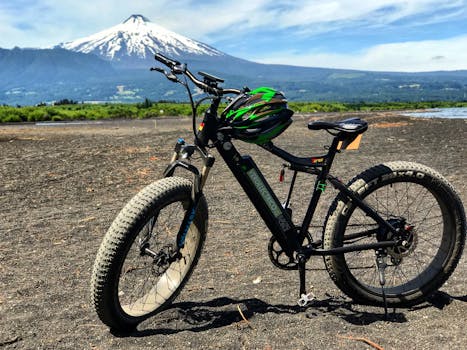 Electric mountain bike parked on rugged terrain with a scenic volcano backdrop.