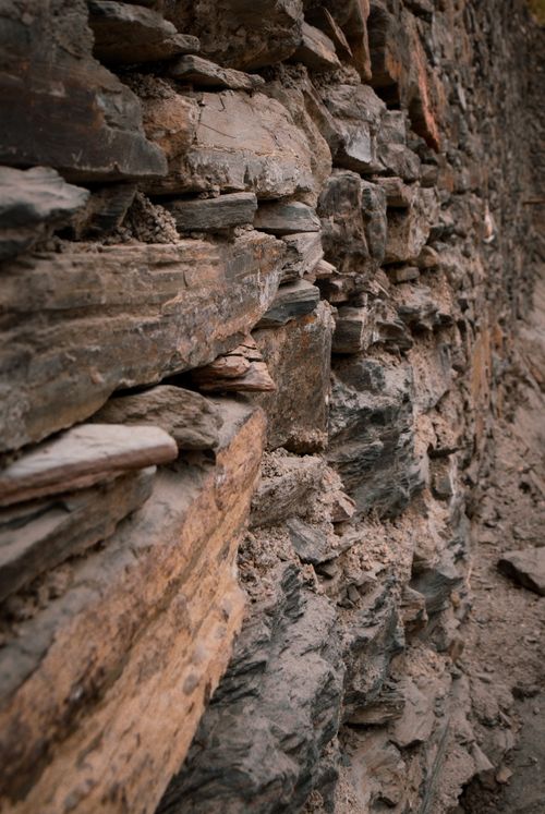 Free Close-up of a naturally eroded stone wall showcasing rough textures and earthy tones. Stock Photo