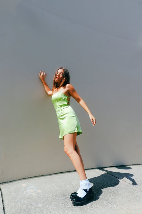 Woman in Green Dress Leaning on Wall and Posing