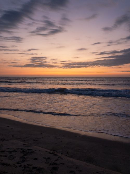 Free Peaceful ocean sunset with soft waves and a sandy beach, perfect for relaxation and tranquility. Stock Photo