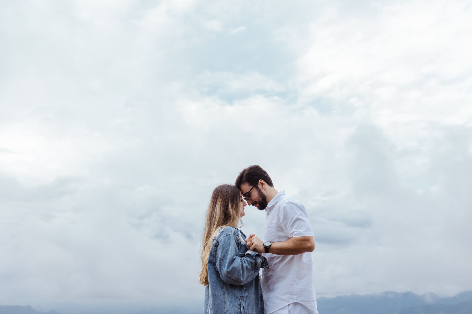 Cute Couple Standing Together Against a Cloudy Sky