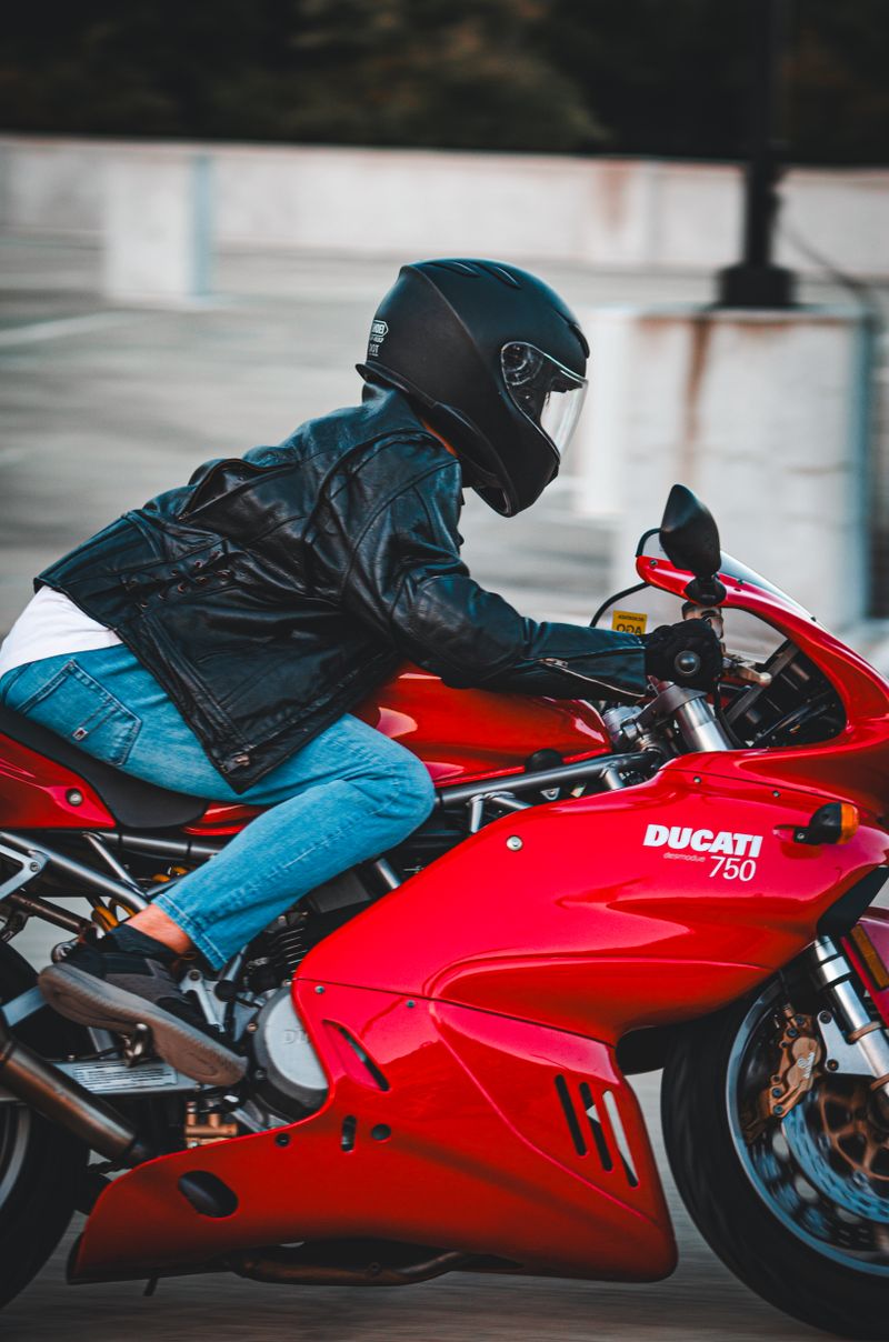 Dynamic image capturing a person riding a red Ducati motorbike at speed