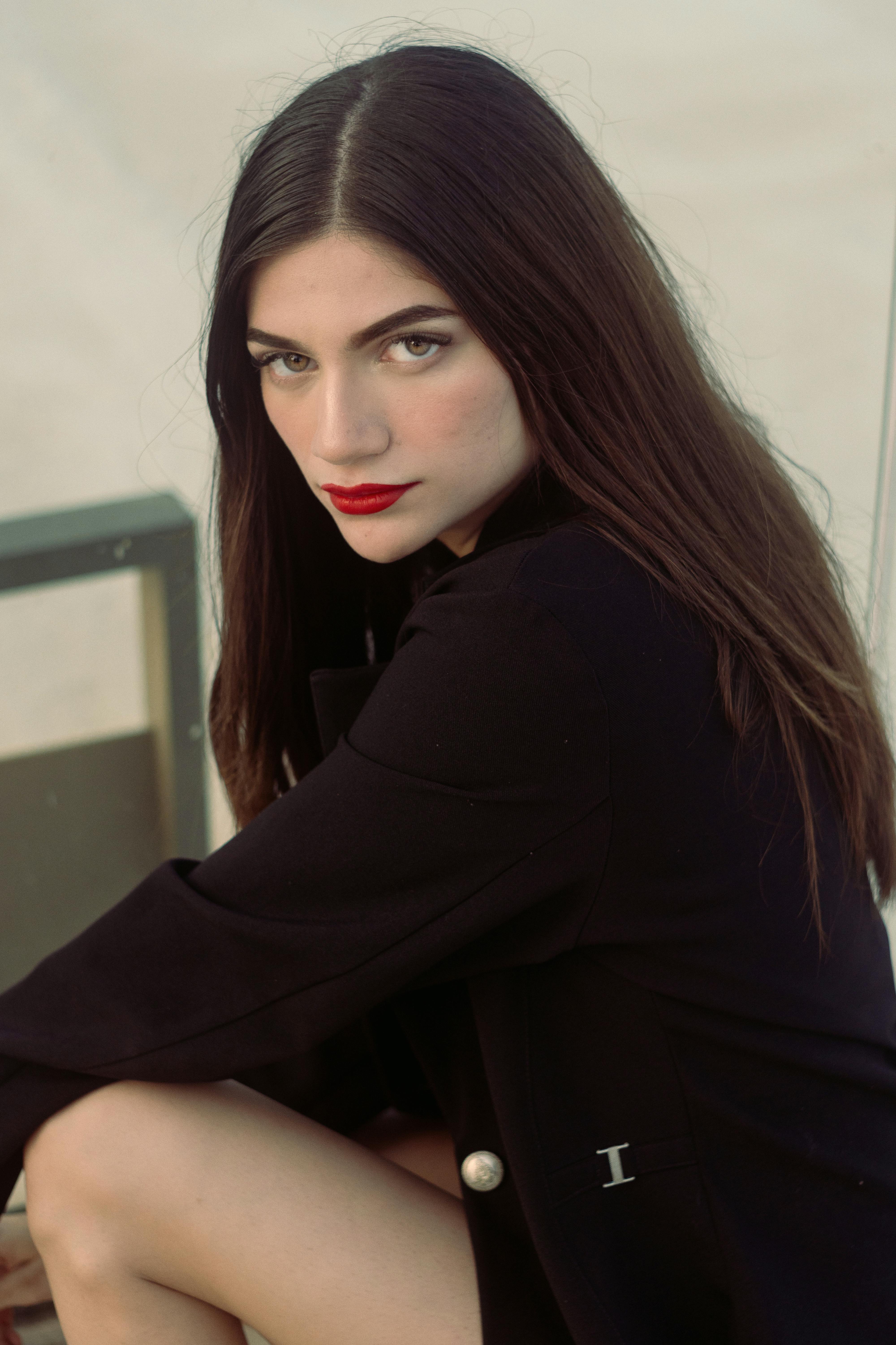 Elegant portrait of a brunette woman with red lipstick posing confidently indoors.