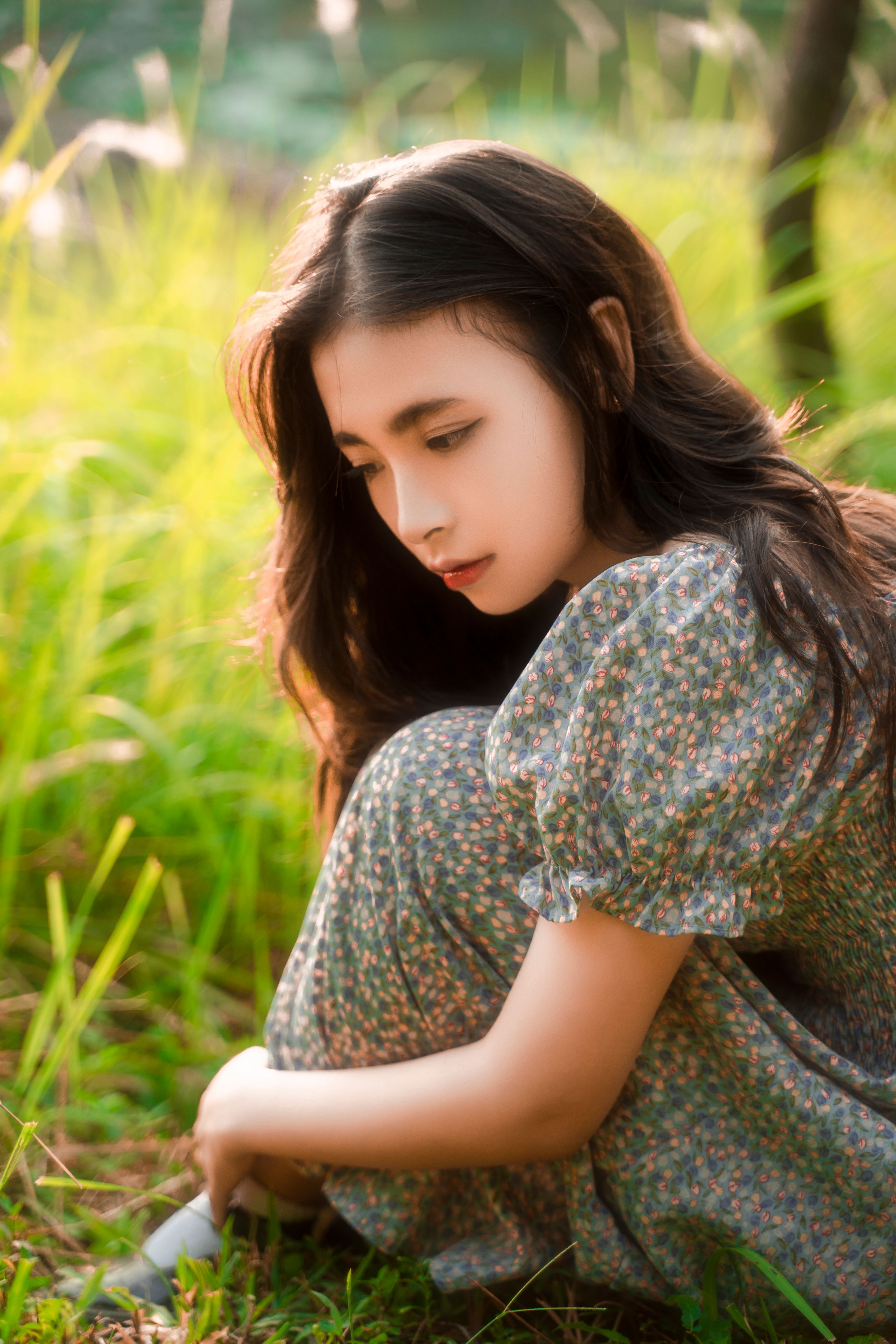 Woman in Green Floral Pattern Dress Sitting on a Lawn · Free Stock Photo