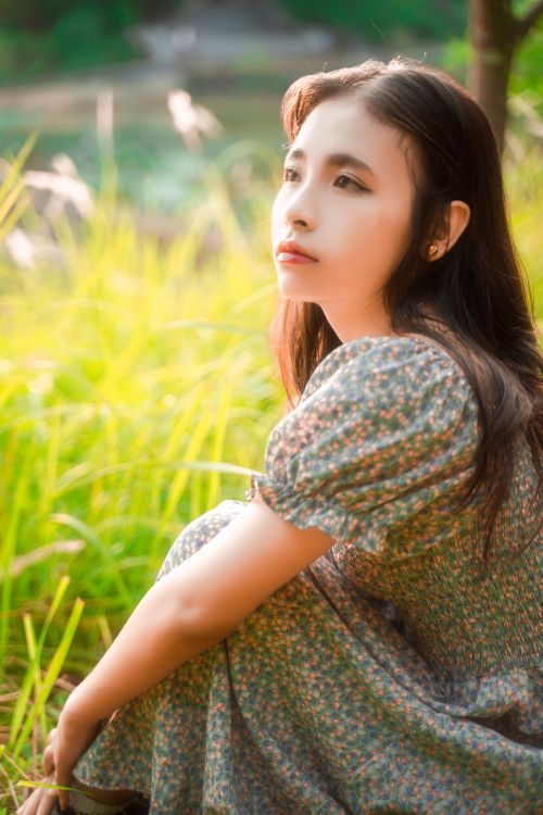 Free A tranquil portrait of a woman sitting in a lush green outdoor setting. Stock Photo