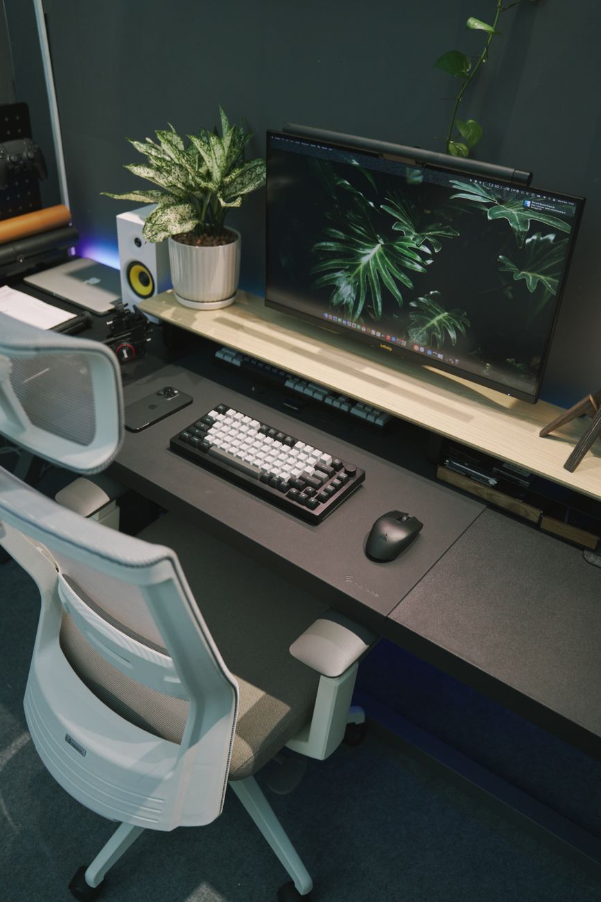 Stylish home office desk with computer, keyboard, and decor for a modern workspace.