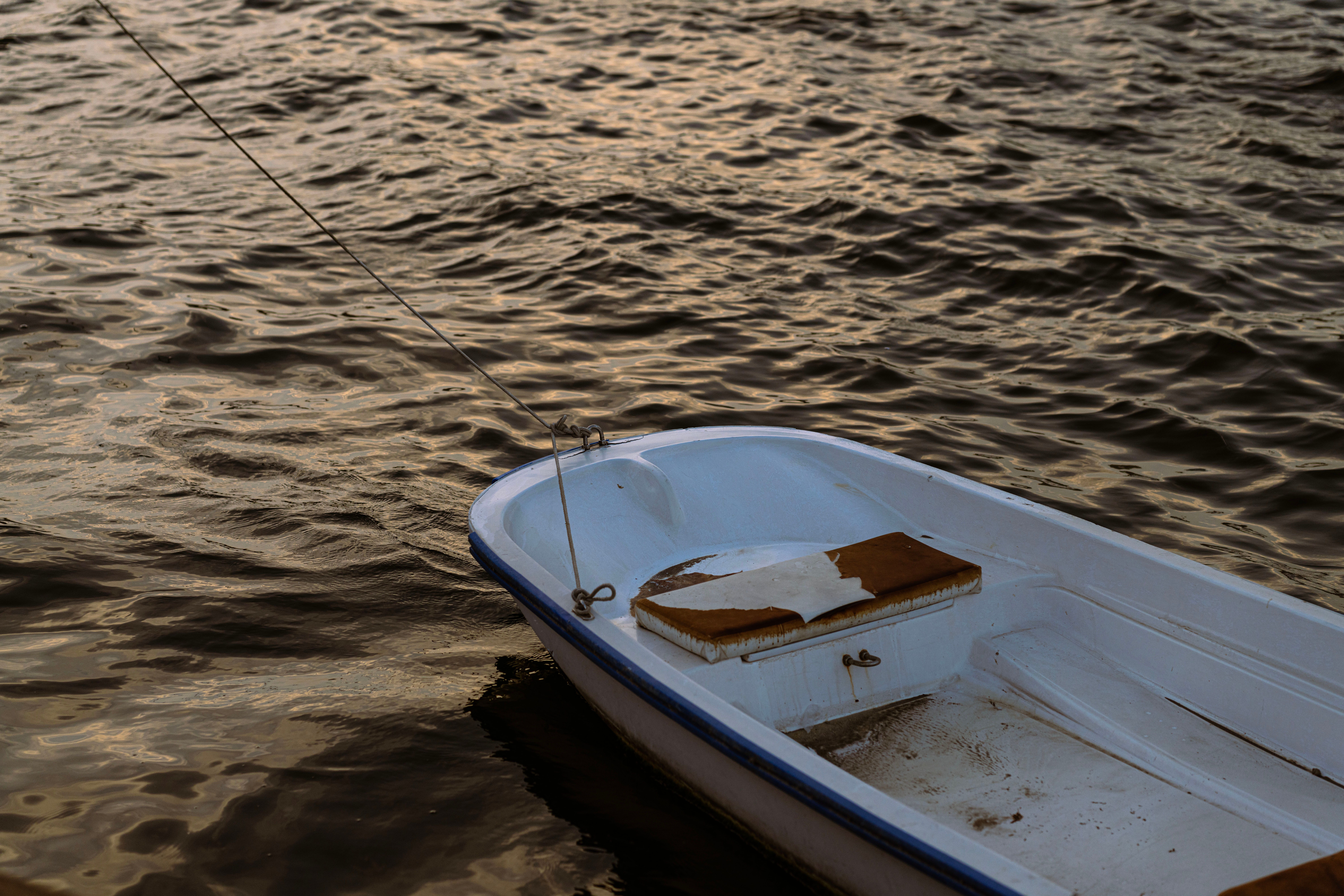 A small boat moored in the calm waters of Dubai at sunset, with rippling water. A small boat moored in the calm waters of Dubai at sunset, with rippling water.