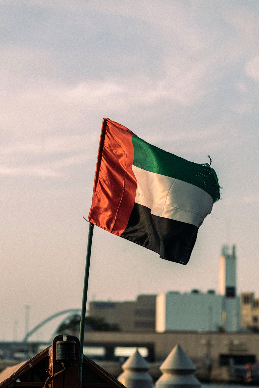UAEThrive Daily News Roundup:United Arab Emirates flag fluttering in a Dubai urban setting, captured during the day.