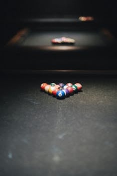 A set of colorful billiard balls perfectly arranged on a dimly lit table, ready for play.