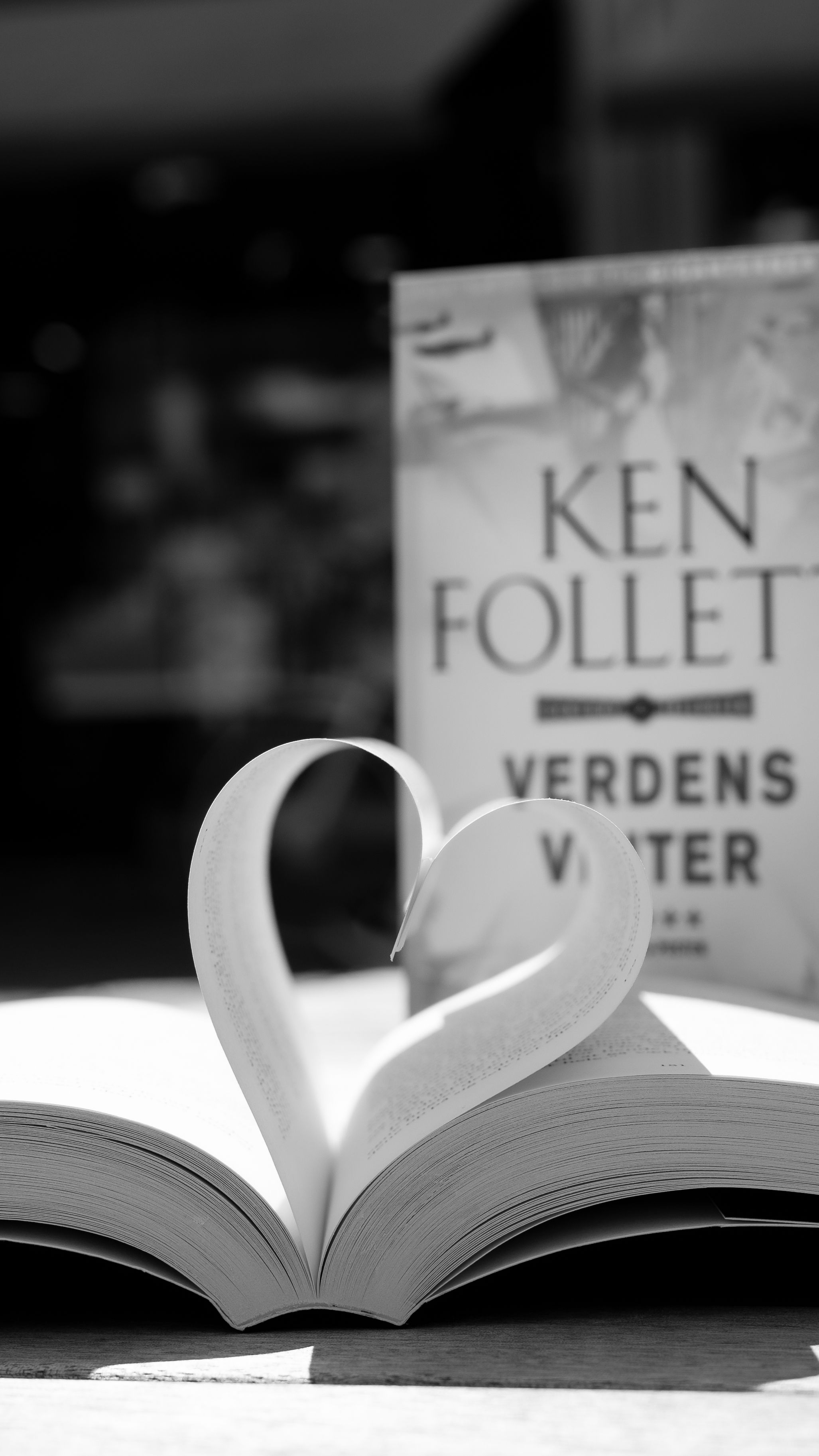 Artistic black and white photo of an open book with pages forming a heart shape. Captivating and romantic.