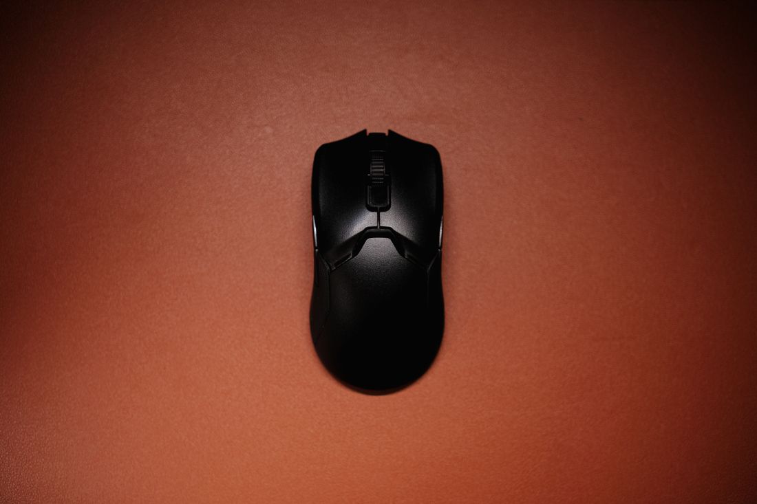 Black wireless mouse on an orange background