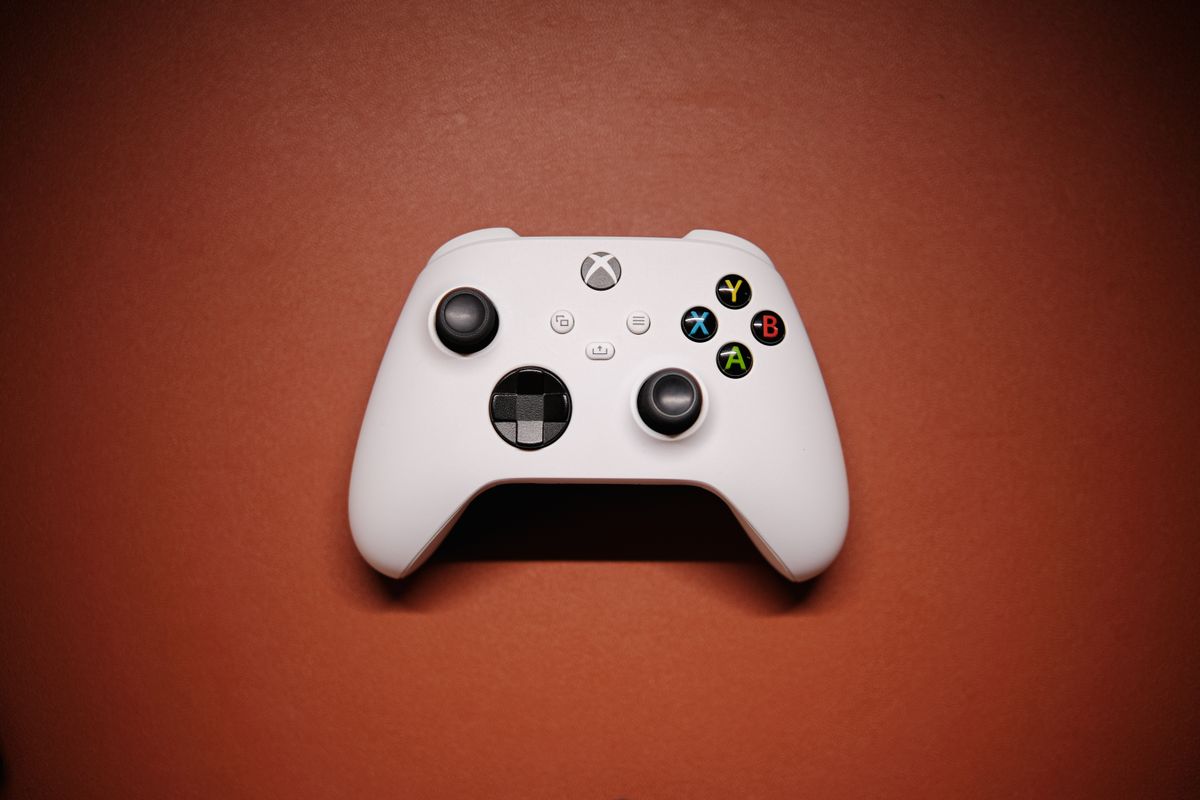 White Xbox controller on a solid red background, illustrative photo