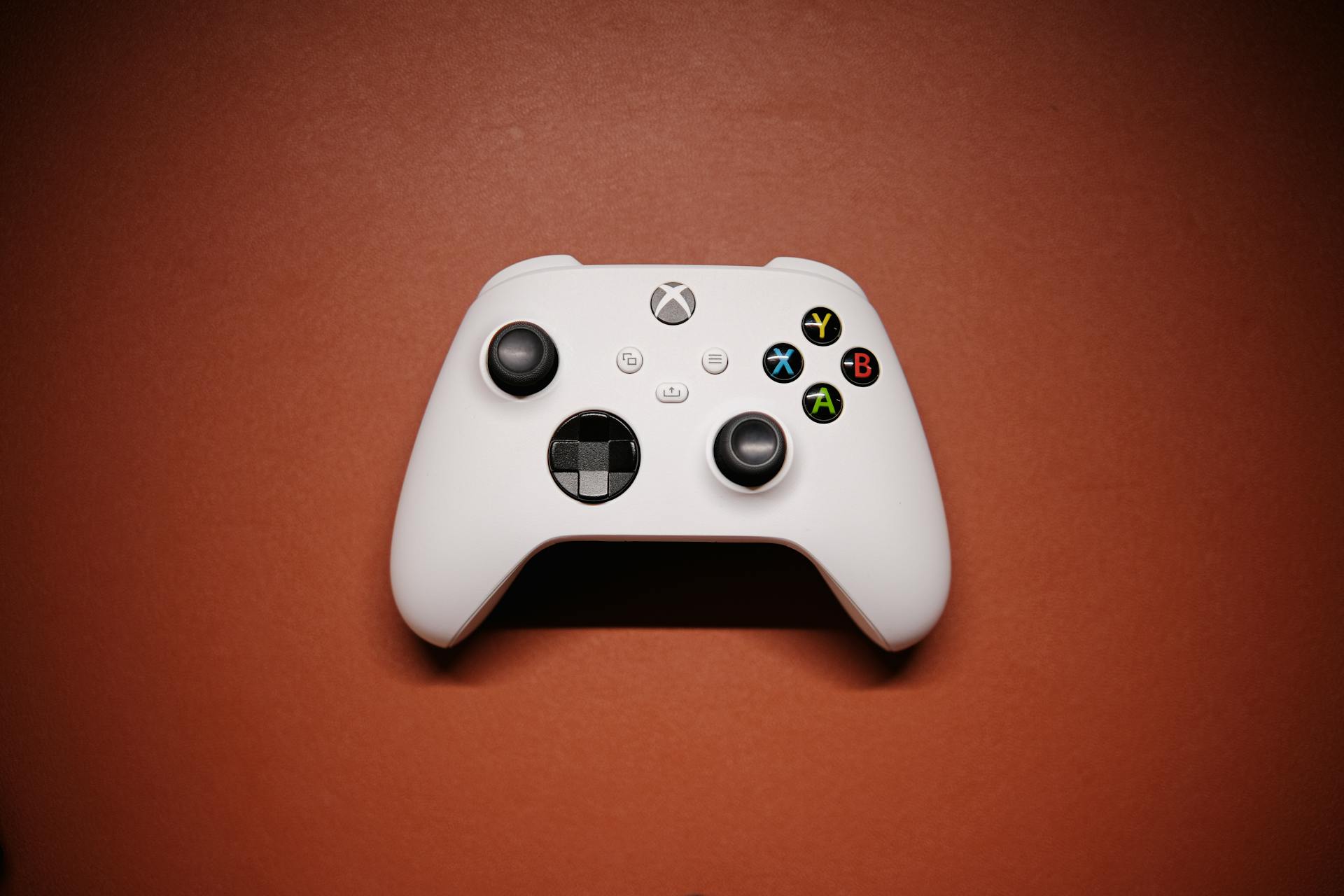 White Xbox controller isolated on a red background with shadows.