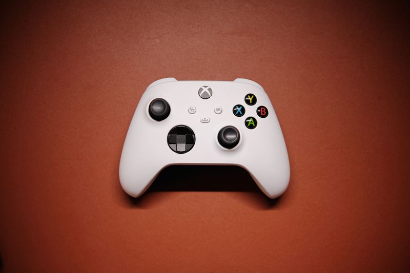 White Xbox controller on a solid red background, illustrative photo