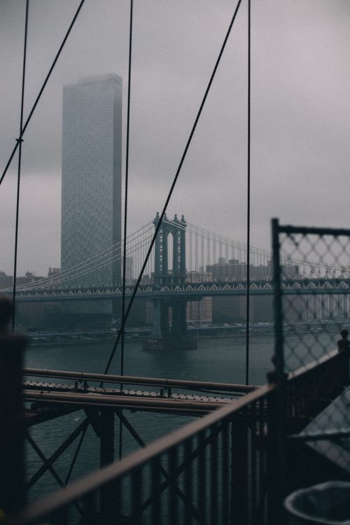 Free Moody view of the Manhattan Bridge and a skyscraper shrouded in mist in New York City. Stock Photo