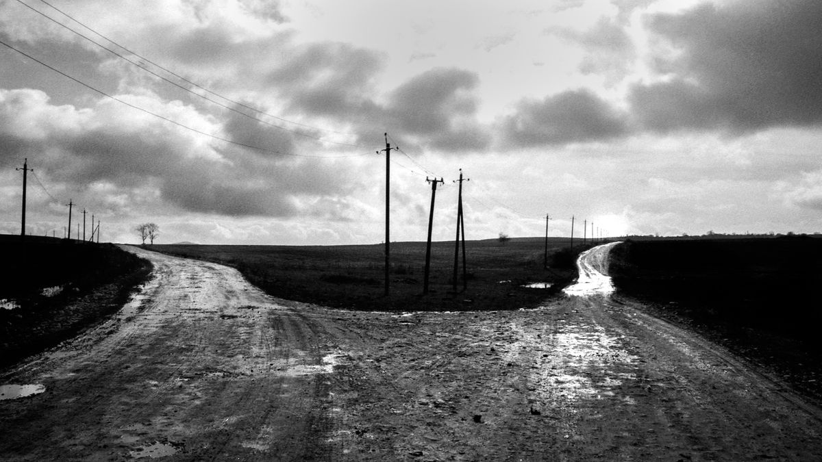 曇り空の下に伸びる分かれ道のモノクロ写真