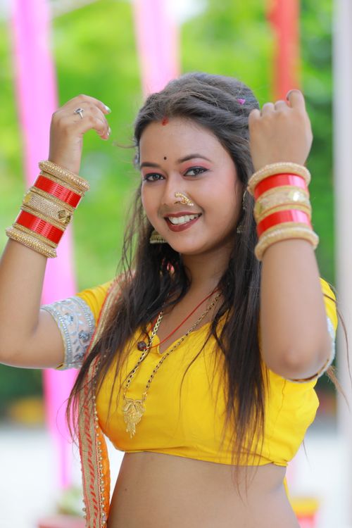 Free A woman in vibrant traditional attire showcasing jewelry and a joyful expression outdoors. Stock Photo