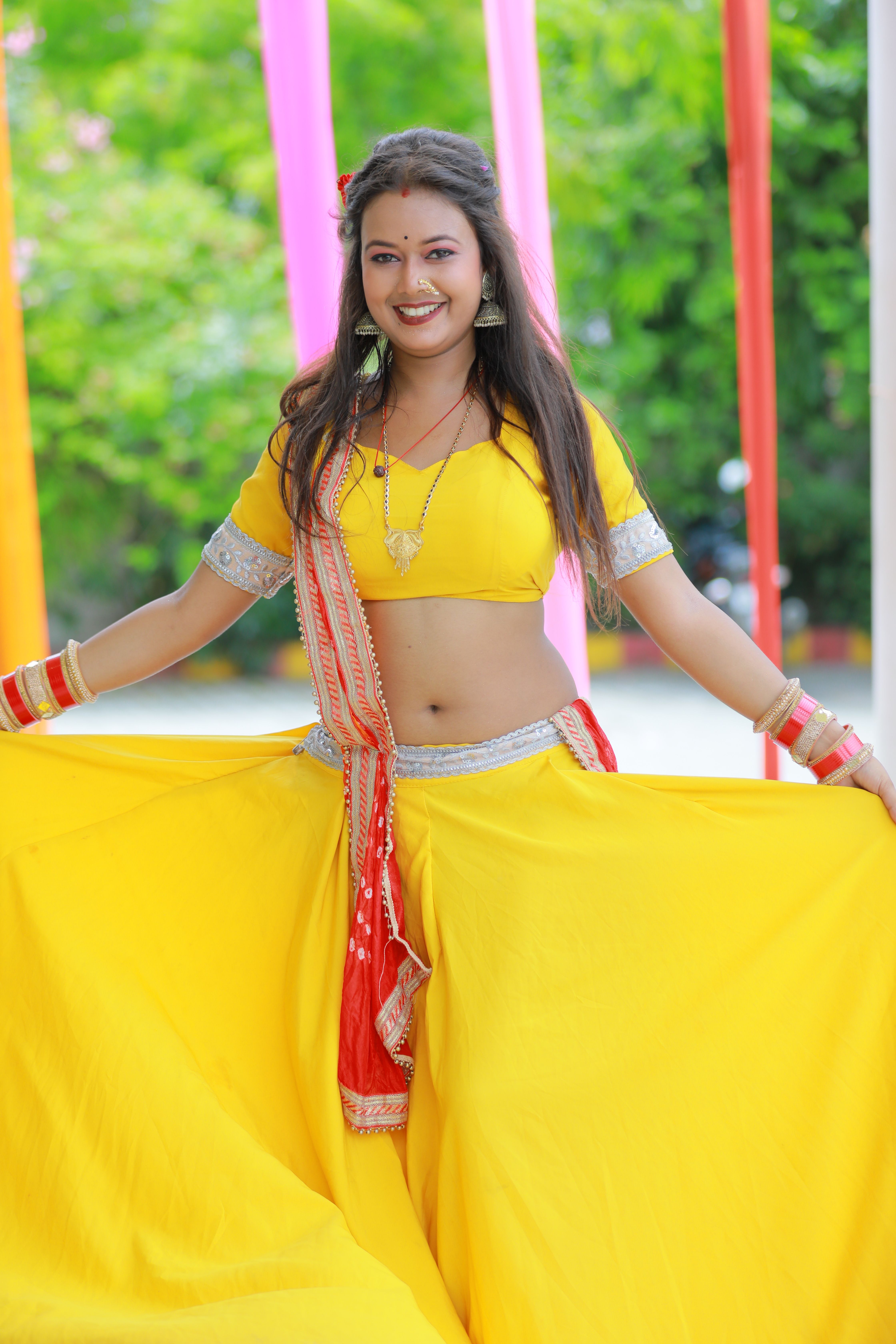 Young woman in colorful Indian attire with a joyful pose outdoors.