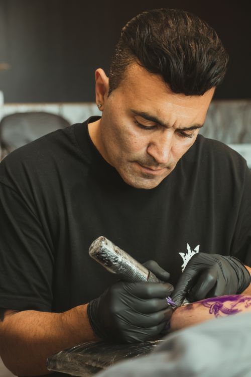 Free A tattoo artist concentrates on creating a detailed tattoo design in a studio. Stock Photo