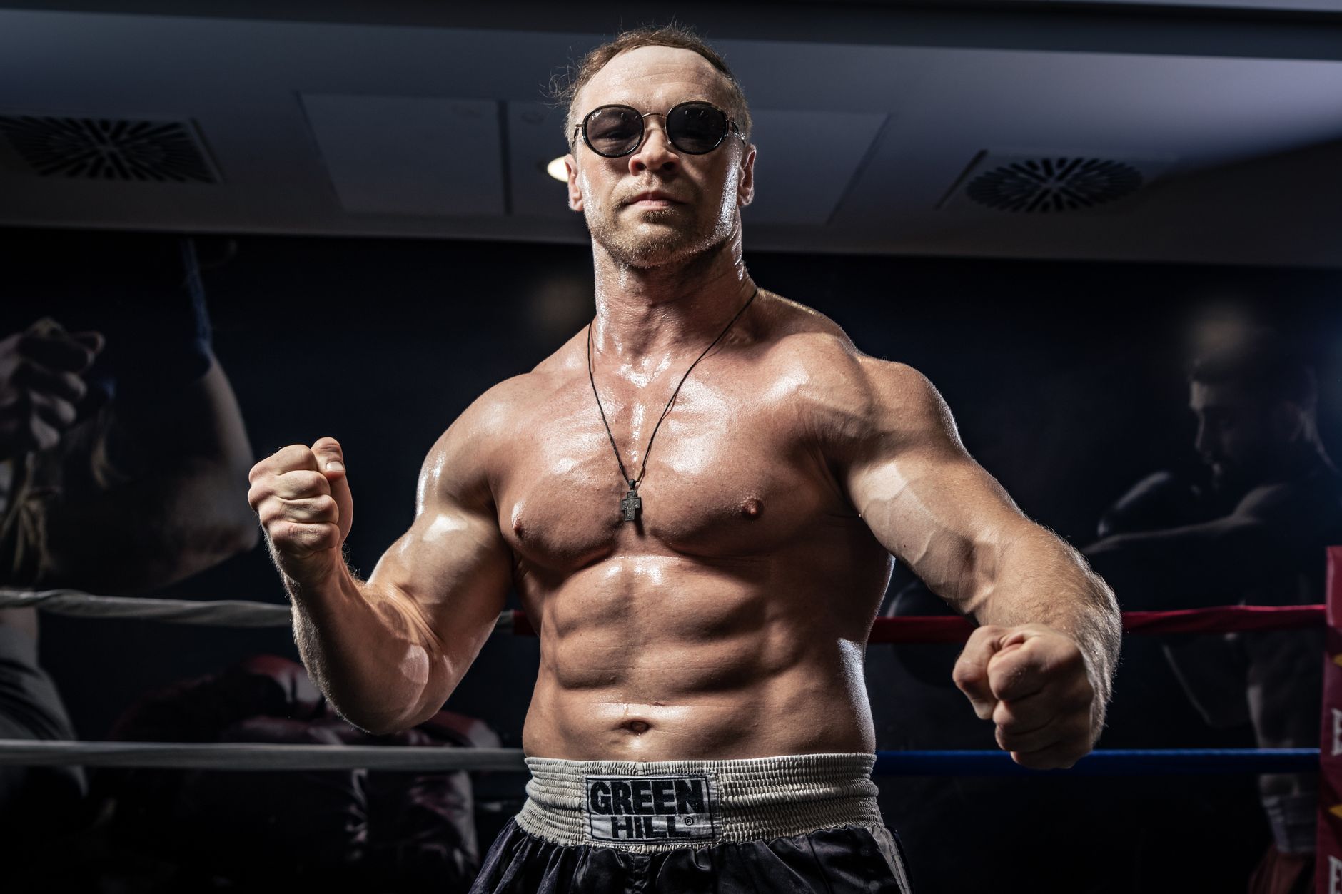 A powerful boxer poses confidently in a boxing ring wearing sunglasses and sports attire.