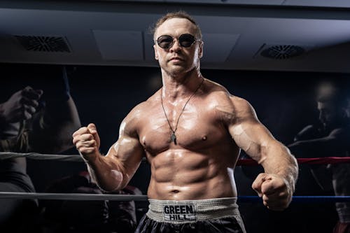 Shirtless Muscular Man in Sunglasses Posing at Boxing Ring