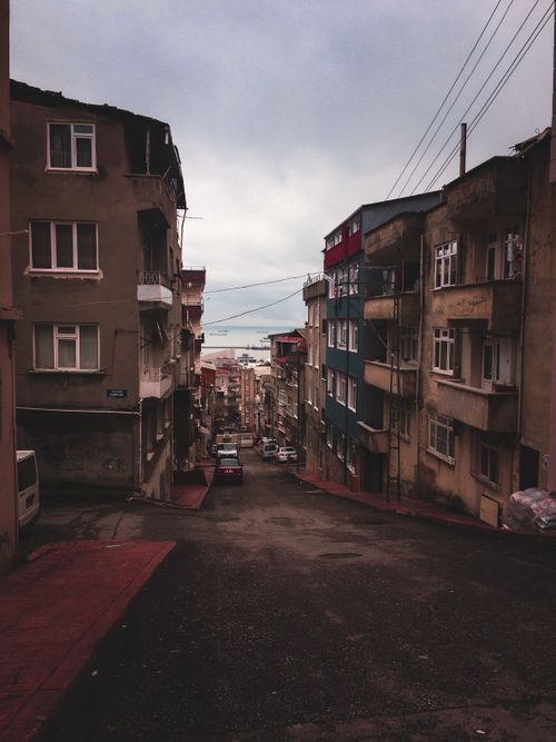 Free A view down a narrow urban street lined with residential buildings, leading to a distant cityscape. Stock Photo