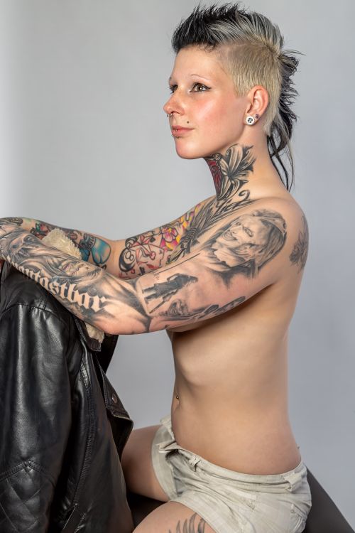 Free Stylish tattooed woman with a mohawk posing confidently in a studio setting. Stock Photo
