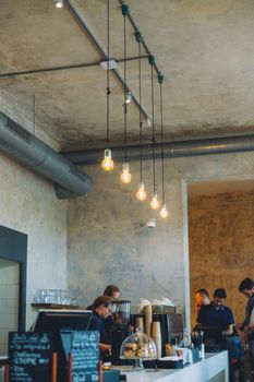 Modern café interior in Prague with people at the counter and industrial lighting.