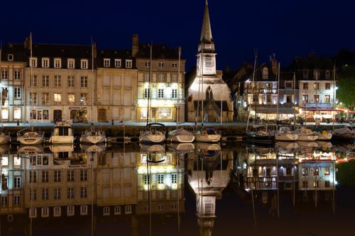 Free Beautiful night scene of Honfleur's harbor with reflections of historic buildings and boats. Stock Photo