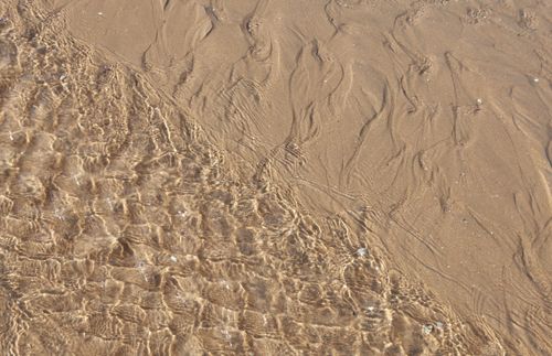 Free Ripples of ocean water meeting sandy shore in Cabourg, Normandy, France. Stock Photo
