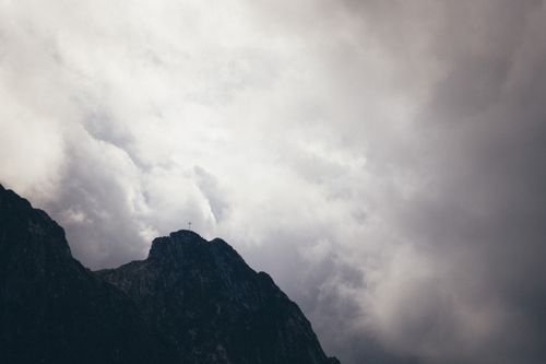Free A captivating view of a mountain peak surrounded by dramatic overcast skies. Stock Photo