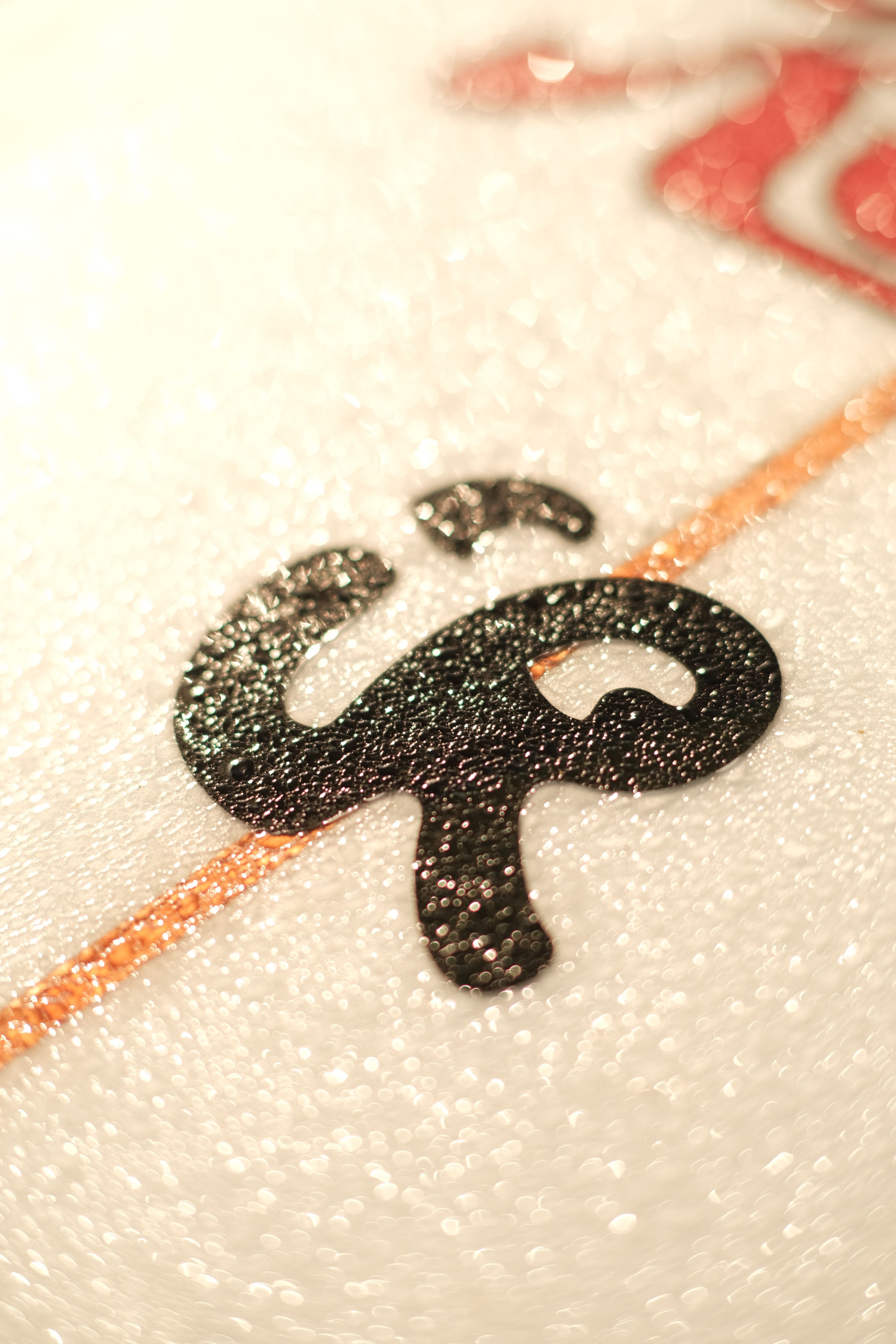 Macro shot of a black textured symbol on a white glittery surface, featuring a vertical line.