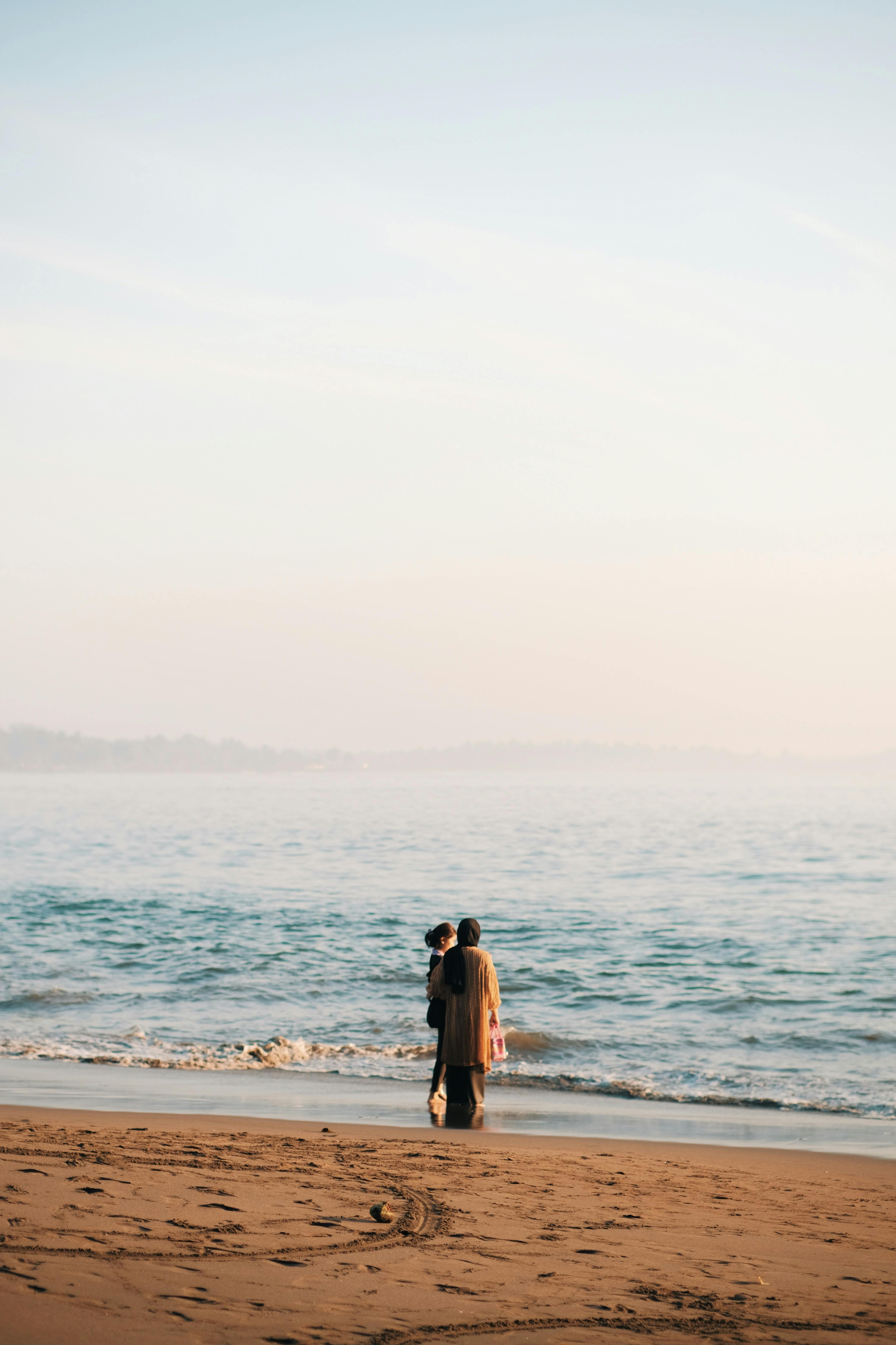 A couple stands on a peaceful beach at sunrise, embracing the tranquility of the ocean view.