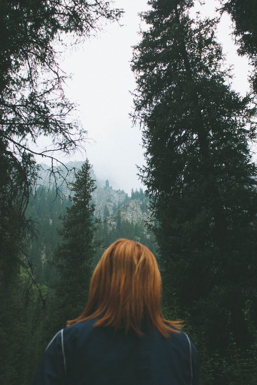 Free A woman with ginger hair gazes at a misty mountain view in Almaty, Kazakhstan. Stock Photo